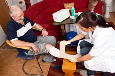 nurse applying bandage to senior's foot